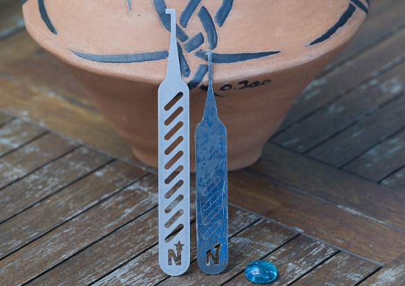 Photo graph of two North Star 4000 on top of a teak table. In the background is a original piece of pottery art by Orval Tso. The North Star 4000 on the right, with the blue tint, is the steel standard variant. The steel variant has been in service for two years. The North Star 4000 on the left is the stainless large variant. 
